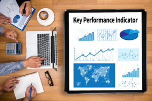 KPI acronym (Key Performance Indicator) Business team hands at work with financial reports and a laptop