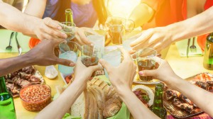 Group of friends toasting with aperitif eating barbecue outdoor - Closeup of hands cheering with cocktails and beers - Friendship,summer,fun and dinner concept - Soft focus on right bottom hand