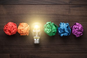 great idea concept with crumpled colorful paper and light bulb on wooden table